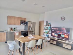a kitchen with a wooden table and white chairs at Grettabril JACO BEACH APARTMENT in Jacó
