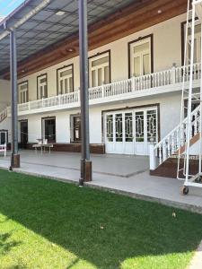 a large white building with a porch and a lawn at Safar Guest House in Samarkand +17 photos