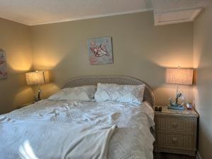 a bedroom with a white bed with two lamps at Cherry Grove condo just steps from the ocean in Myrtle Beach +9 photos