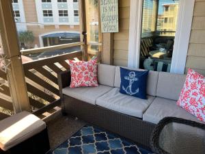 a couch on a porch with pillows on it at Cherry Grove condo just steps from the ocean in Myrtle Beach