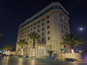 a large building with palm trees in front of it at Le Vendome Hotel in Amman