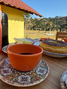 an orange bowl sitting on a table with a cake at Pousada Fazenda coronel in Camanducaia