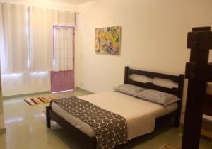 1 dormitorio con 1 cama y una pintura en la pared en Pouso do Sopé, en Paraty
