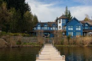 a blue house with a dock in front of the water at Las Balsas Relais & Chateaux in Villa La Angostura