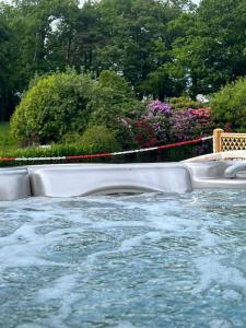 una grande piscina d'acqua in un giardino con alberi di Charming retreat with hot tub and lake terrace a Hilderstone
