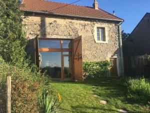 an external view of a stone house with a large glass door at La Belle Grange de Cuzy in Cervon