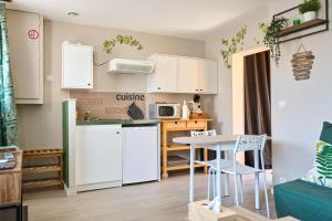 a small kitchen with white cabinets and a table at Studio le ginkgo in Anet