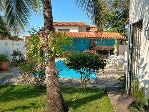a house with a palm tree and a swimming pool at Casa do Sol, luz e Vida. in Saquarema