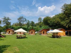 a group of lodges with tables and umbrellas in the grass at CAMPING THOBIAS in Boşorod