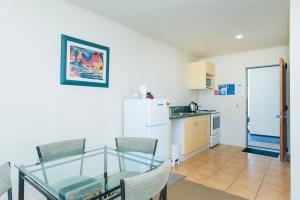 a kitchen with a glass table and chairs and a refrigerator at Alfresco Motor Lodge in Gisborne