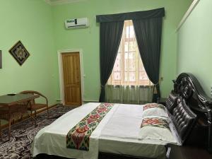 Un dormitorio con una cama y una mesa y una ventana. en Shukrona Guest house, en Bukhara 20 fotos más