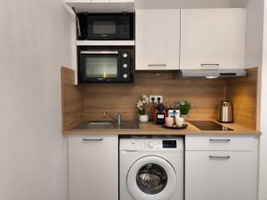 a kitchen with a washing machine and a microwave at Magnifique Studio Douillet in Le Mans +8 photos