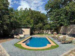 a swimming pool with chairs and a table and trees at VILLAge GOGHT in Goghtʼ