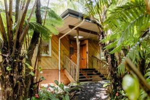 a wooden house with a staircase leading to the front door at Hale Kumu La'au- A'a in Volcano