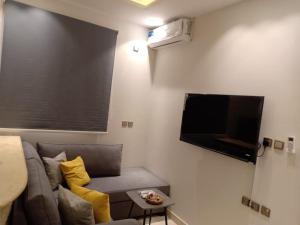 a living room with a gray couch and a flat screen tv at Dorm Story For Hotel Apartment in Taif
