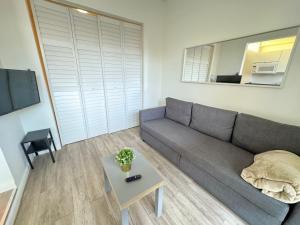 Una sala de estar con un sofá gris y una mesa. en Villas at Auxilio Mutuo 103, en San Juan
