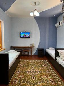 a room with two beds and a tv on a wall at Minorai Xurd in Bukhara +43 photos