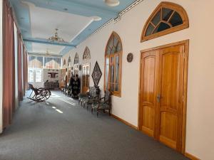 Un pasillo vacío con sillas y una puerta de madera. en Shukrona Guest house, en Bukhara