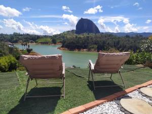 two chairs sitting on the grass near a lake at Cabaña Estancia Primavera in Guatapé
