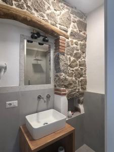 a bathroom with a sink and a stone wall at Crispi Guest House MMG in Olbia