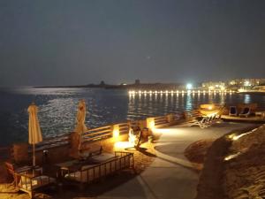 a group of tables and umbrellas next to the water at night at Mountain View 1 /Ain El Sokhna in Ain Sokhna