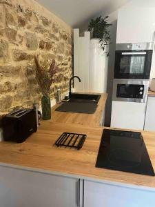 a kitchen with a counter with a sink and a stove at Gîte en pierre avec baignoire balnéo in Plonéour-Lanvern