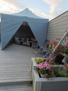 a blue tent with chairs and flowers on a deck at 3-roms leilighet, innsjekk uten vert. Egen inngang in Ålesund