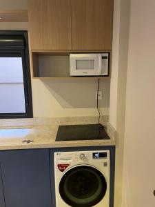 a kitchen with a microwave and a washing machine at Studio Central Todo Planejado com Ar Condicionado in Bagé