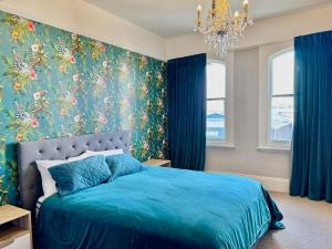 a bedroom with a blue bed with a floral wallpaper at The Italian Warehouse in Oamaru