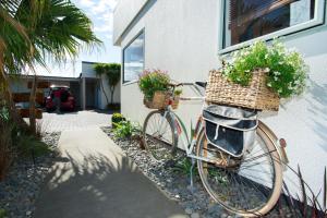 rower zaparkowany przed domem z kwiatami w koszach w obiekcie Alfresco Motor Lodge w mieście Gisborne