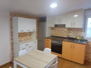 a kitchen with white cabinets and a table and a stove at Corme camiño dos faros, playa Galicia in Corme-Puerto