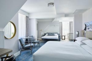 a white hotel room with a bed and a mirror at Bournemouth Highcliff Marriott Hotel in Bournemouth