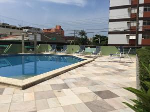 a swimming pool with chairs on a building at Apartamento Vereda Tropical in Guarujá