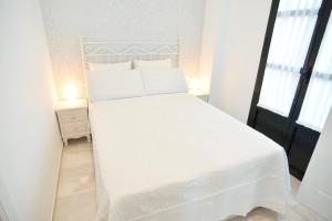 a white bed with white sheets and pillows in a bedroom at Macarena Home in Seville
