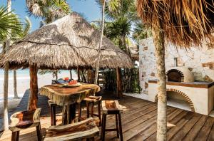 a patio with a table and chairs and a pizza oven at Casa de Los Vientos Soliman Bay in Tulum