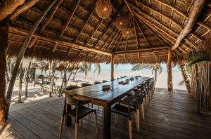 a long table in a straw hut on the beach at Casa de Los Vientos Soliman Bay in Tulum