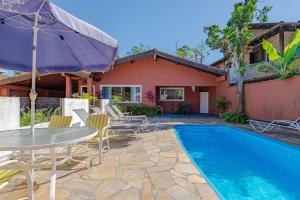 a patio with a table and chairs and a pool at 4 dorm com piscina a 350 m de Camburizinho in Camburi