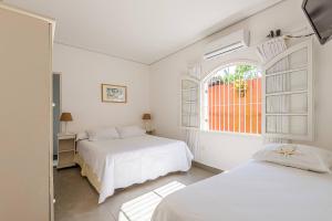 a white bedroom with two beds and a window at 4 dorm com piscina a 350 m de Camburizinho in Camburi +119 photos
