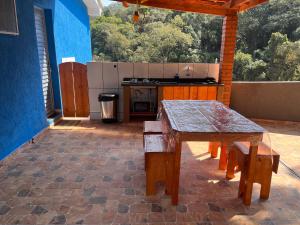an outdoor patio with a table and a kitchen at Chalé Canto da Viola in São Roque