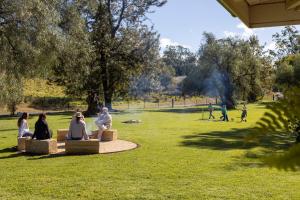 a group of people sitting on benches in a park at Glenoak Cottage in Sparkes Creek