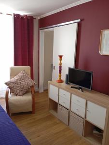 a living room with a television and a chair at Aliciamar E by Casas de Setúbal in Setúbal