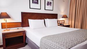 ein Hotelzimmer mit einem Bett und einem Tisch mit einer Lampe in der Unterkunft Metropolitan Hotel in Teresina