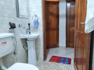 a bathroom with a sink and a pair of shoes on the floor at Rose Pearl Apartment in Entebbe +44 photos