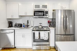 Una cocina con gabinetes blancos y un refrigerador de acero inoxidable. en Quiet Kingston Getaway - 3 Mi to Beaches!, en Kingston