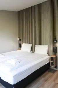 a bedroom with a large white bed with a striped wall at Hestheimar in Hella