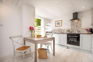 a kitchen with a wooden table and chairs and a table and a counter at Lavender Cottage in Porthscatho