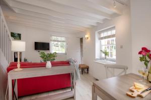a living room with a red couch and a table at Lavender Cottage in Porthscatho