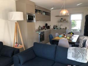 ein Wohnzimmer mit einer blauen Couch und einer Küche in der Unterkunft Maison dans le sud du Morbihan près de la mer in Damgan + 13 Fotos