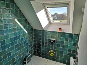 ein Bad mit grünen Fliesen und einem Fenster in der Unterkunft Maison dans le sud du Morbihan près de la mer in Damgan
