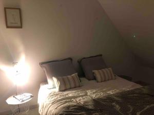 ein Schlafzimmer mit einem Bett mit zwei Kissen und einer Lampe in der Unterkunft Maison dans le sud du Morbihan près de la mer in Damgan